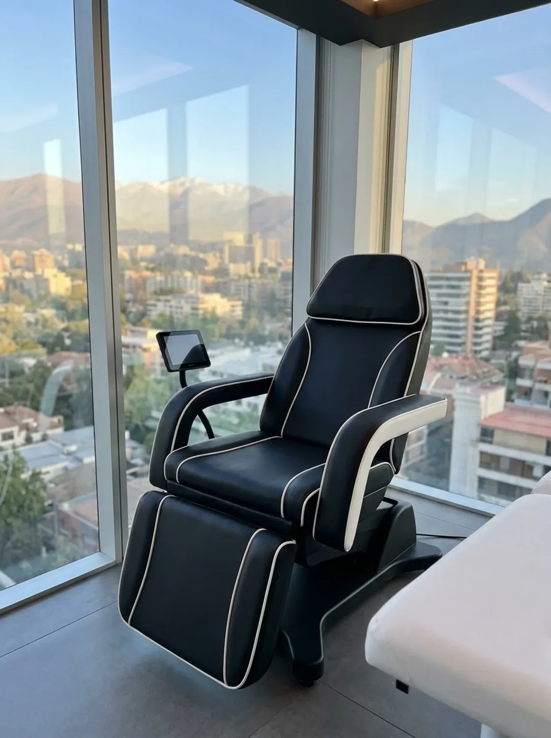 La silla PelviX™ del box de Spark, vacía, junto al ventanal con la cordillera y la camilla clínica